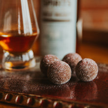 Dark chocolate bourbon ball aka a truffle, is blended with Lifted Spirits Wheat Whiskey and contains a whiskey soaked maraschino cherry inside.  Rolled in sugar and finished with a sprinkle of red luster dust.  Delicious! Kansas City gifts.  Bourbon Chocolate.  Bourbon Balls.  Bootleg Bourbon Balls